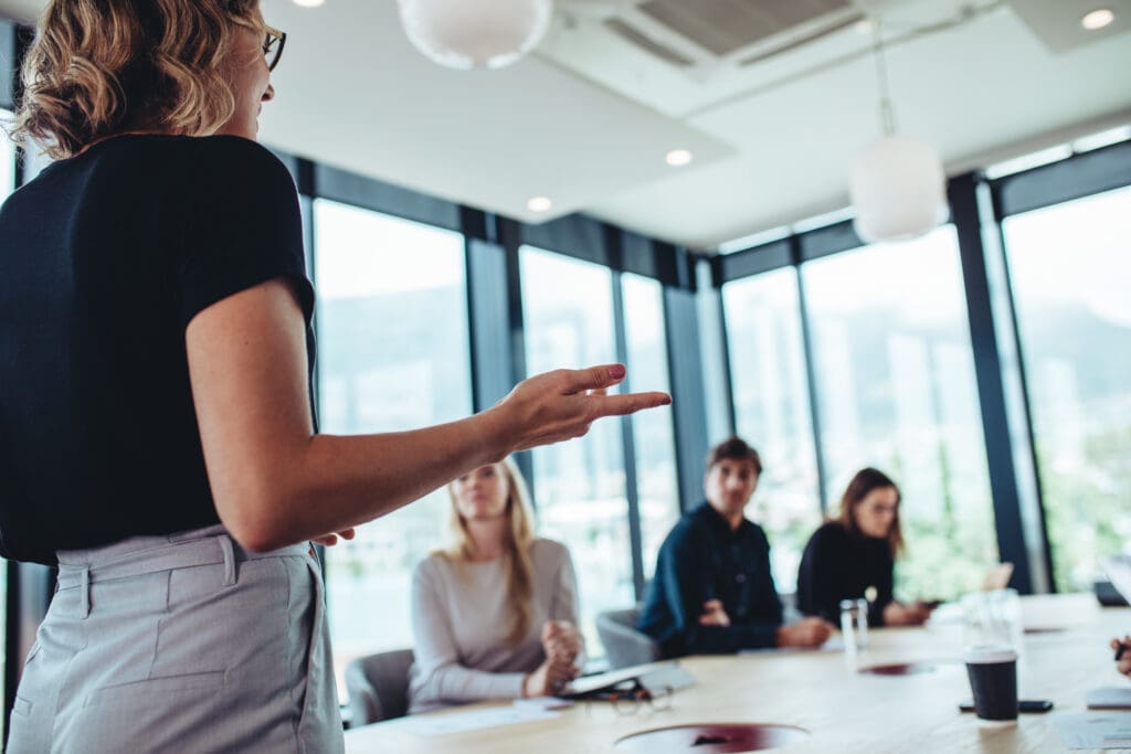 Woman standing in a board room delivering a story to a group of people