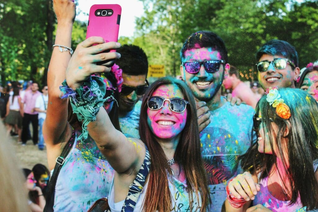 Group of young adults covered in neon paint taking a selfie at a festival