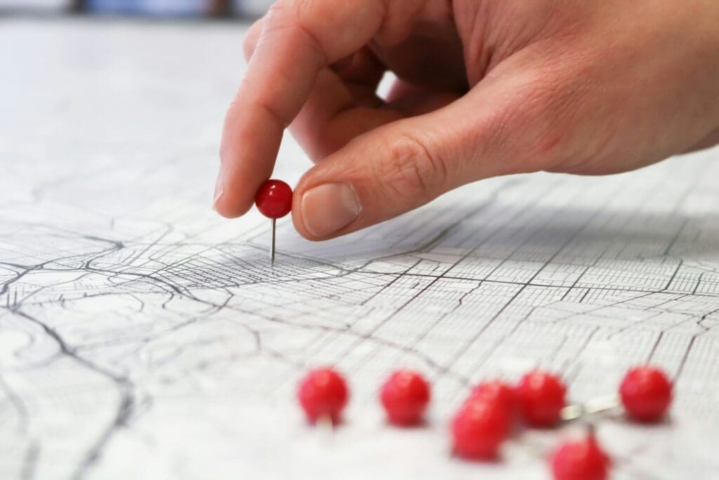 Hand placing a red pin on a map to represent local SEO strategies.